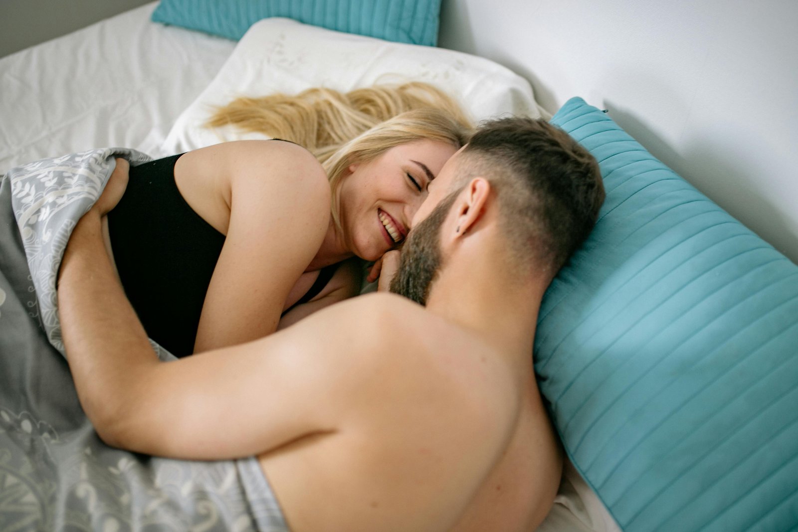 Mann und Frau kuscheln im Bett als Wellnessprogramm