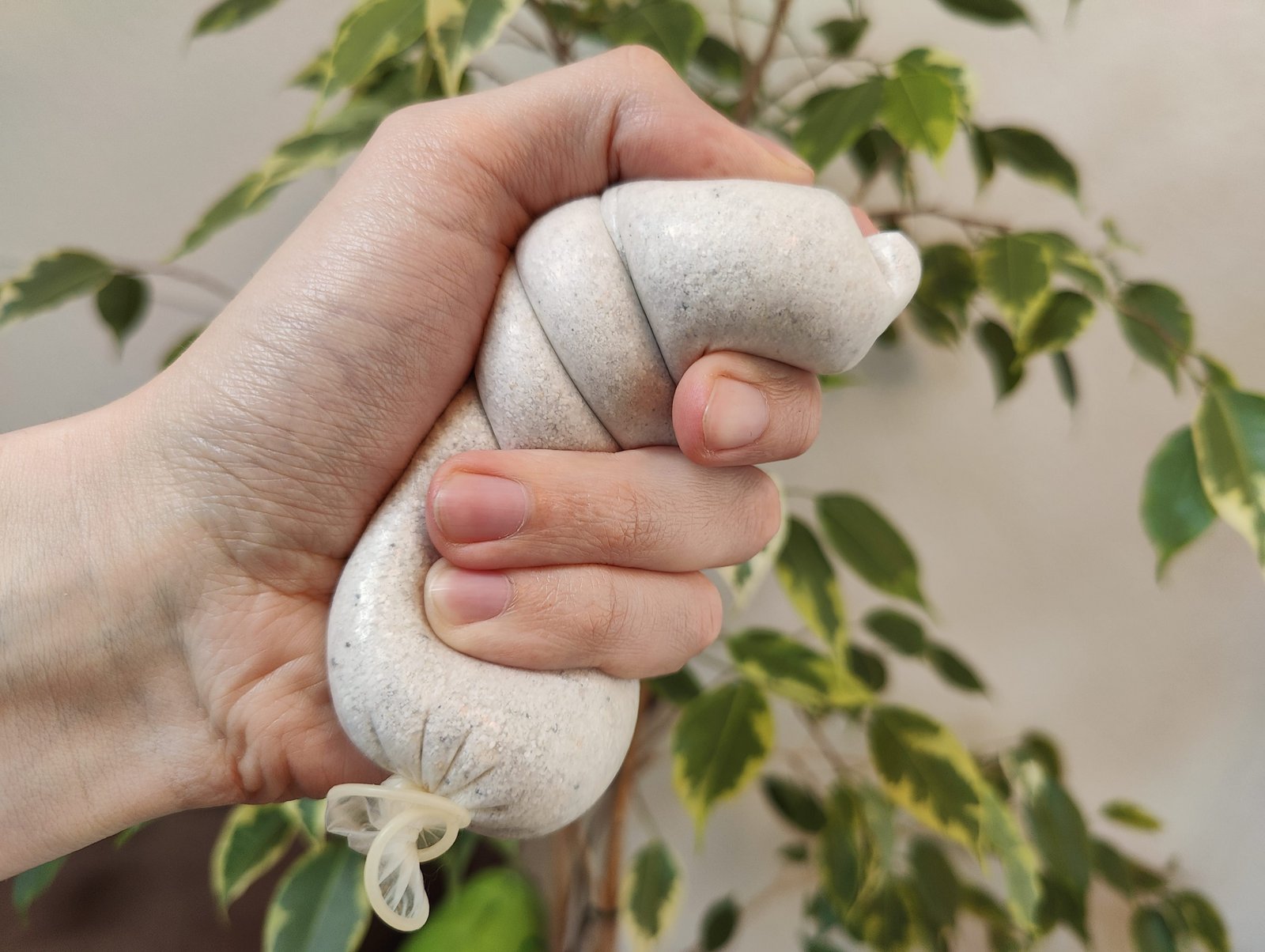 Ein abgelaufenes Kondom mit Sand gefüllt, in der Hand von jemandem, der es als Stressball benutzt